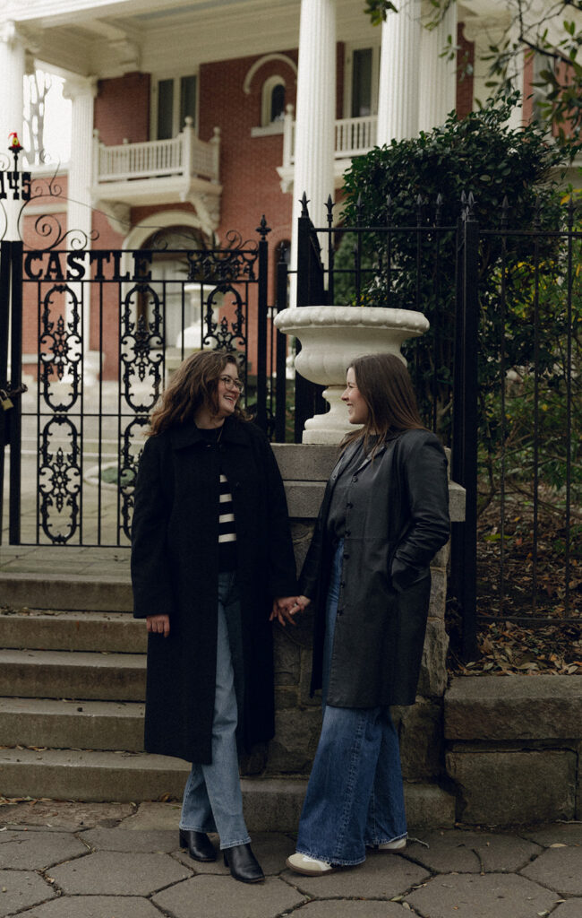 A candid moment of an engaged LGBTQ+ couple laughing together on a tree-lined street in Inman Park, Atlanta. The natural sunlight and documentary-style composition capture their joyful connection.”
