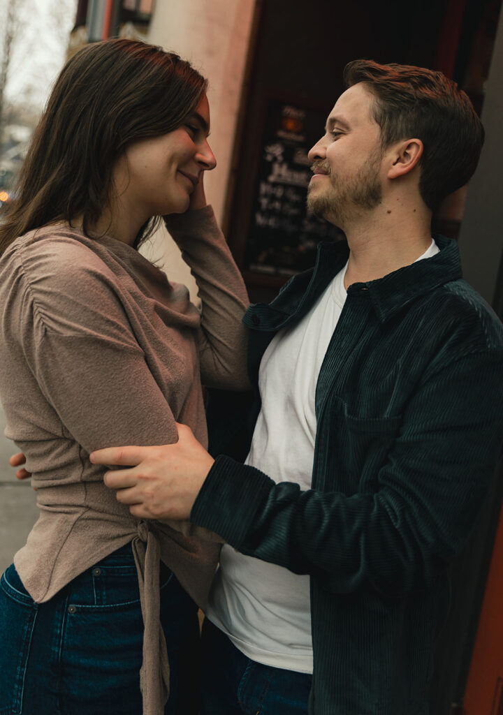 Couple smiling at each other under holiday lights in Virginia Highlands