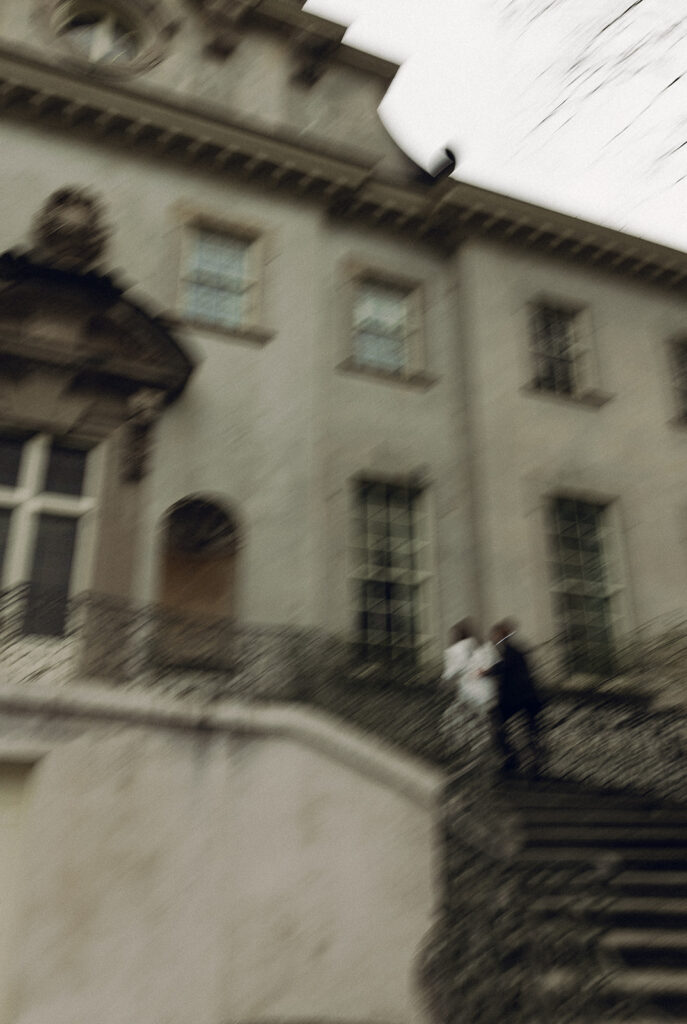 Blurry photo of couple walking up swan house stairs during engagement session