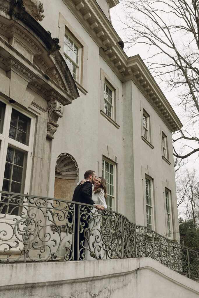 Victoria and Ross laughing on the grand staircase at the Swan House in Atlanta during their engagement session