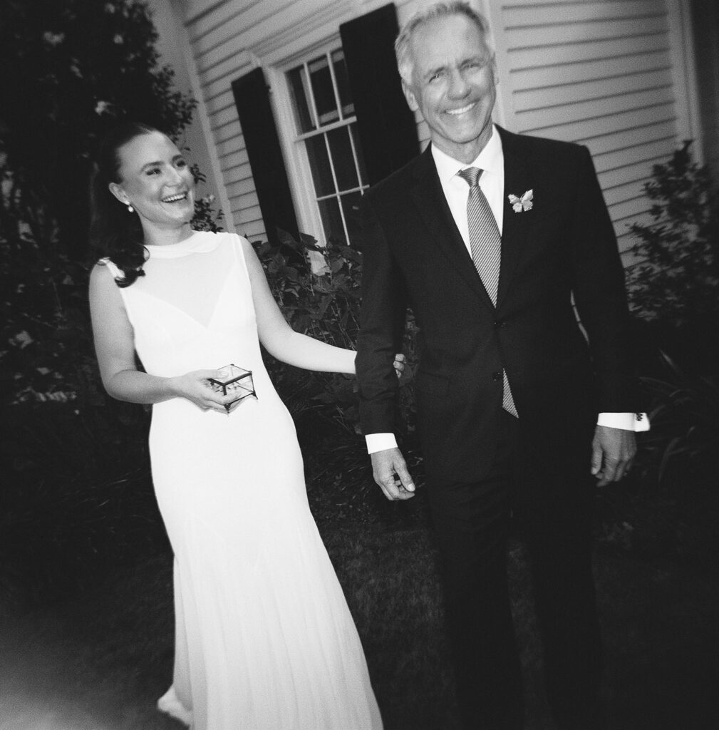 Bride laughing with her father during a candid moment captured on black and white film
