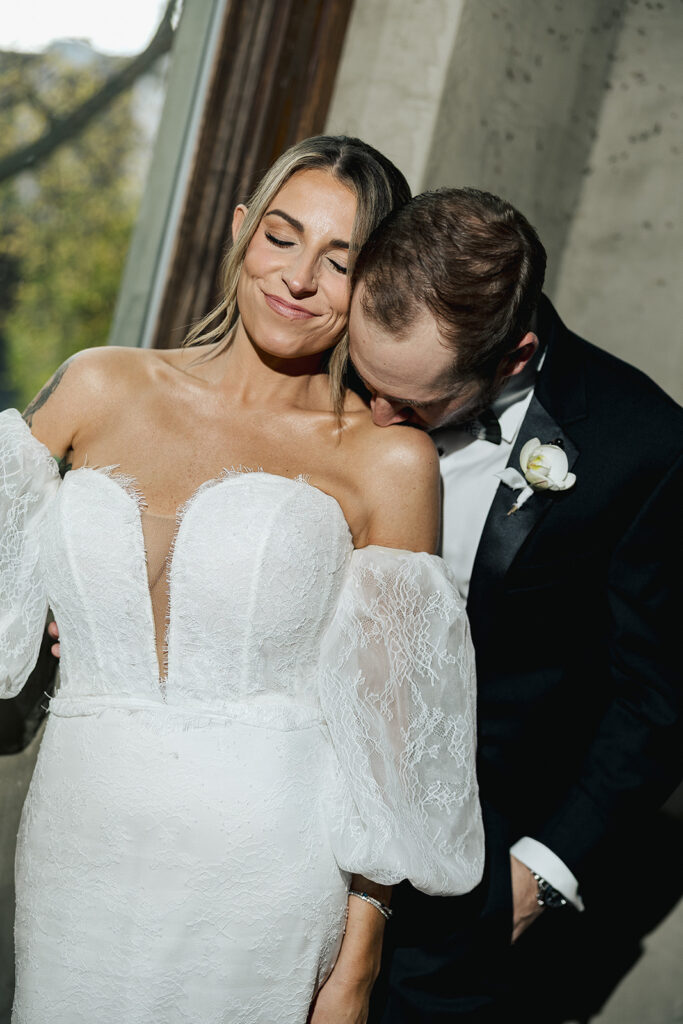 Bride and groom standing close together in window light, sharing a quiet, intimate moment during portraits.
